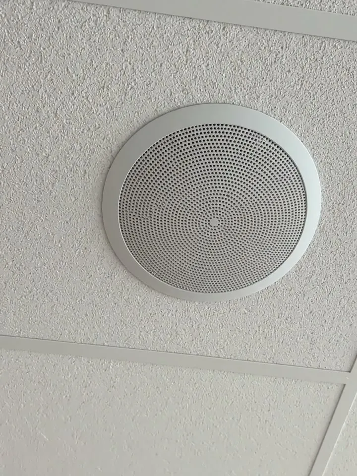 A round ceiling speaker in a suspended ceiling tile