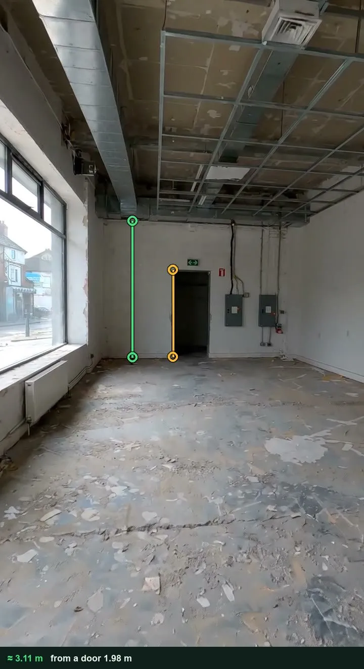 The back wall of the room marked up with an amber line on the door and a green line from the floor to the underside of the grid, about 3.11 m