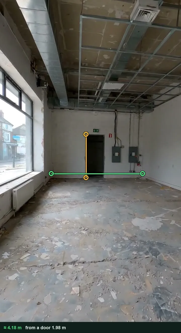 The back wall of an empty training room under fit-out, marked up with an amber line on the door and a green line across the wall, about 4.18 m
