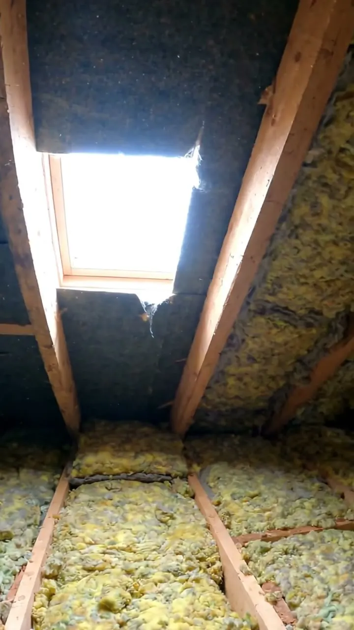 Daylight showing through torn felt between rafters in a roof space with mineral wool insulation
