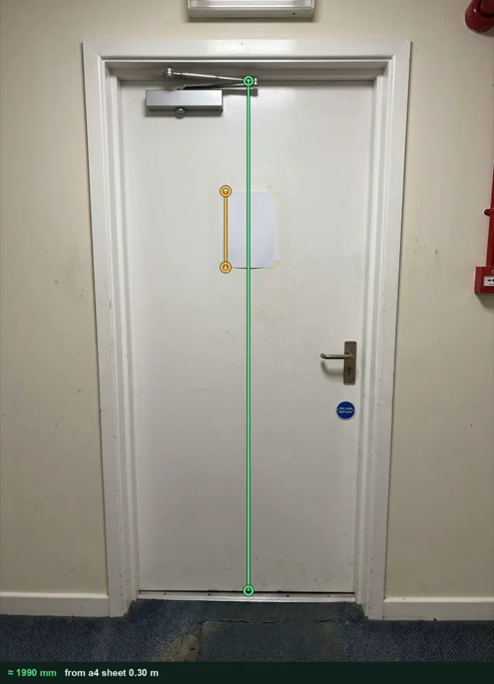 A white fire door with an A4 sheet taped to it, measured from the photo at about 1990 mm from the head of the leaf to the threshold
