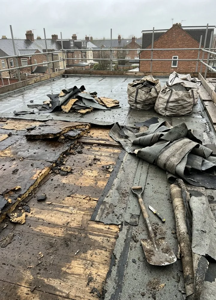 A strip of new torch-on cap sheet laid on a flat roof deck with the old felt stripped back beside it