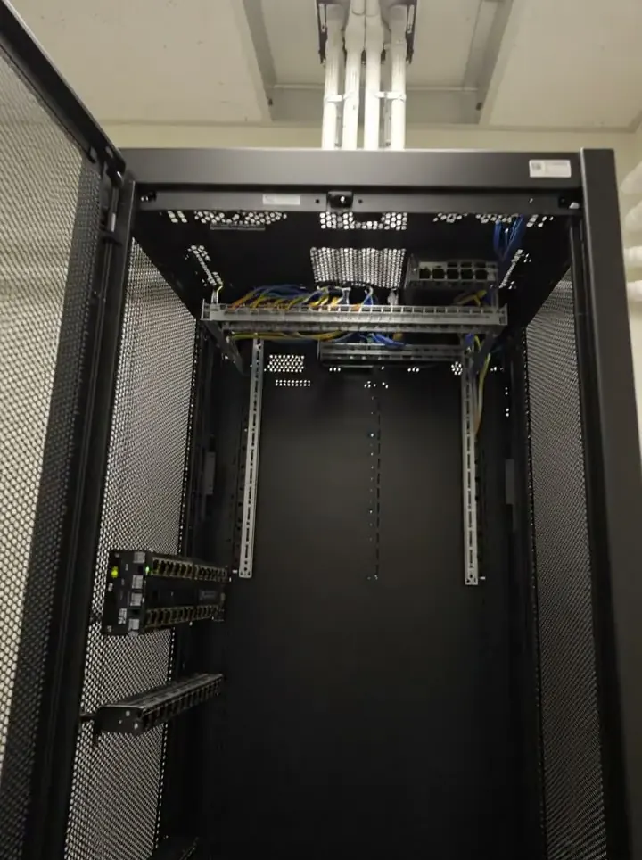 An open 42U comms cabinet in a small white room