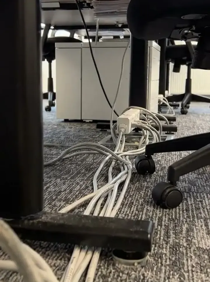 A floor box under desks with cables trailing from it