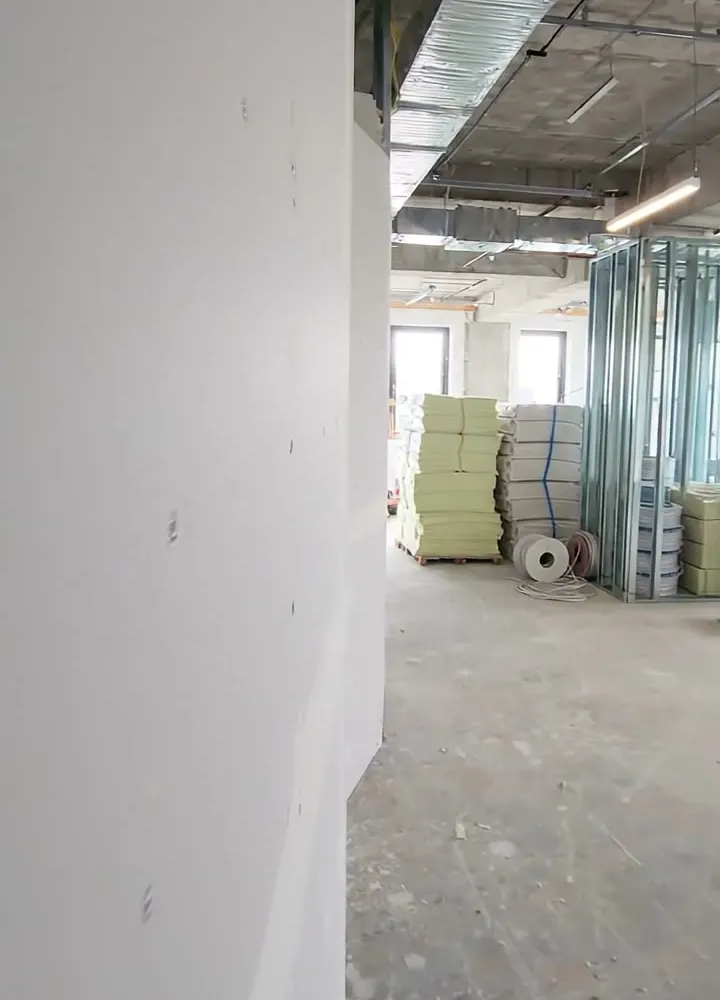 A boarded partition running up to the slab with the head detail visible above the ceiling line