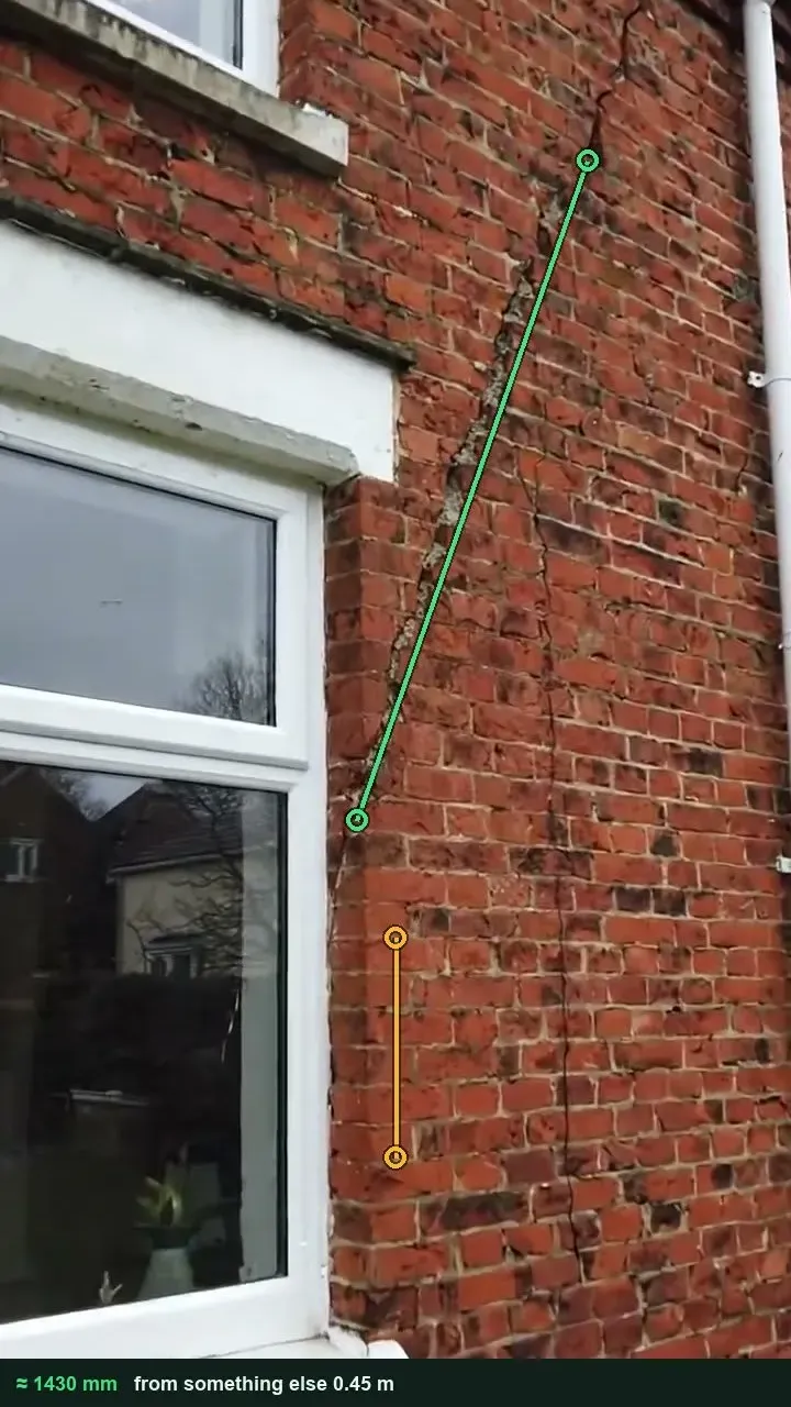 Brick rear wall with a diagonal crack rising from a window head, marked with a green measuring line and a six-course brick reference