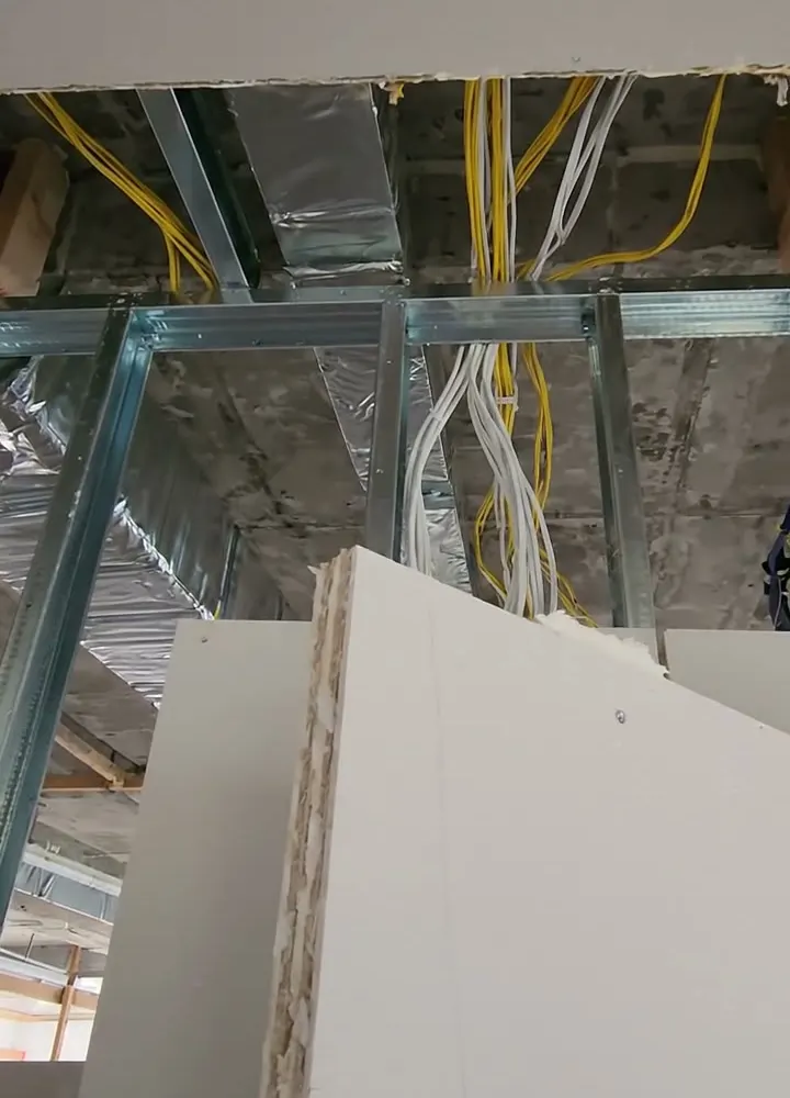 A plasterboard partition stopping short of the slab with cables passing through the open head