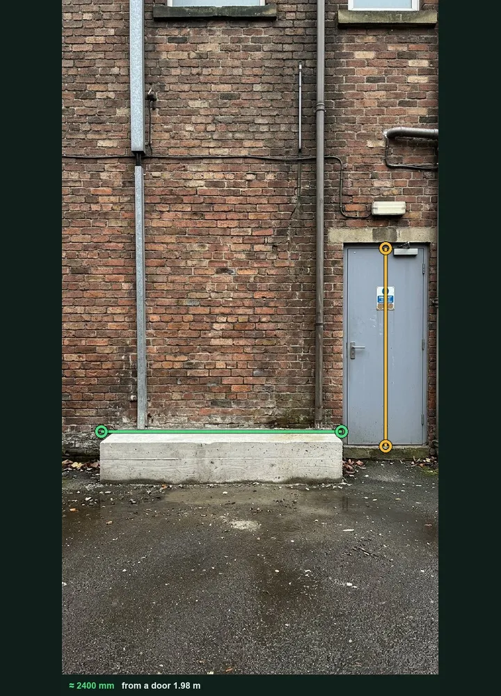 A service yard wall marked up in Measure from photo: an amber line on the door and a green line along a concrete plinth, about 2,400 mm