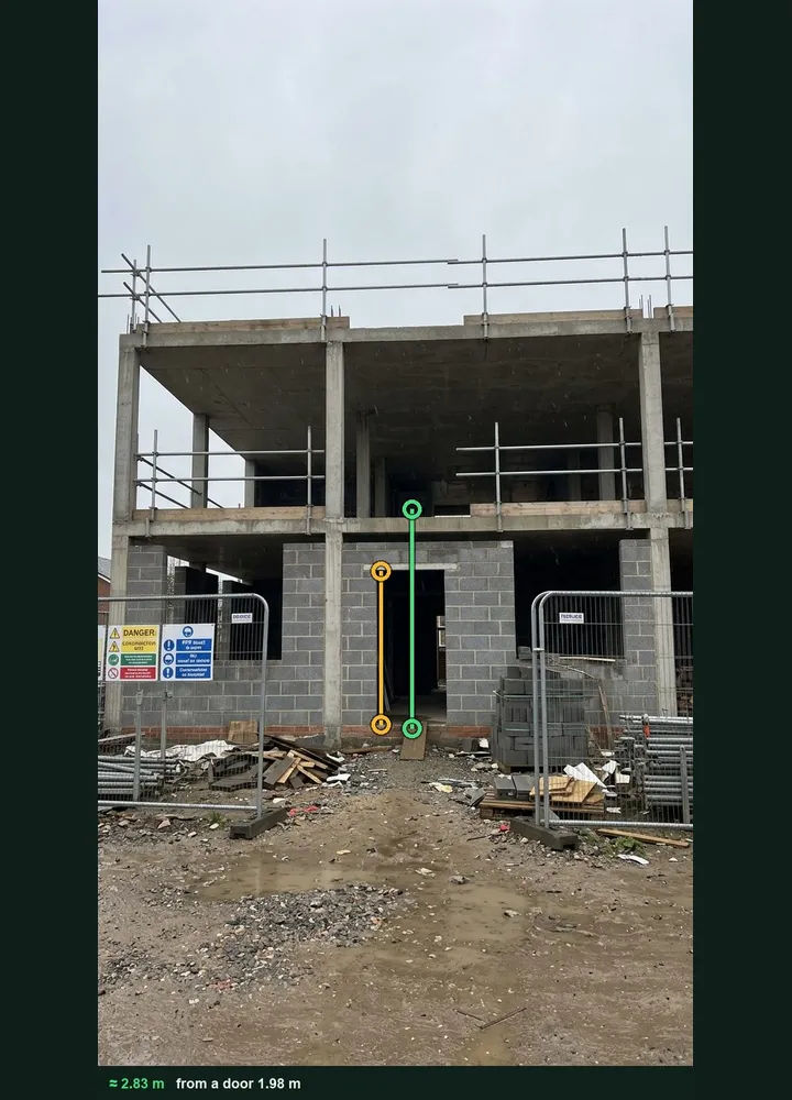 A two storey concrete frame marked up in Measure from photo: an amber line on the ground floor doorway and a green line from the ground to the first floor slab edge, about 2.83 m