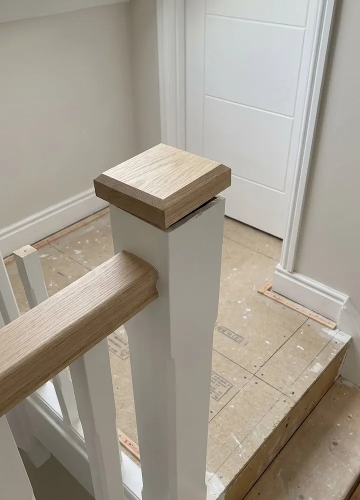 The top of a new white staircase with a loose oak newel cap