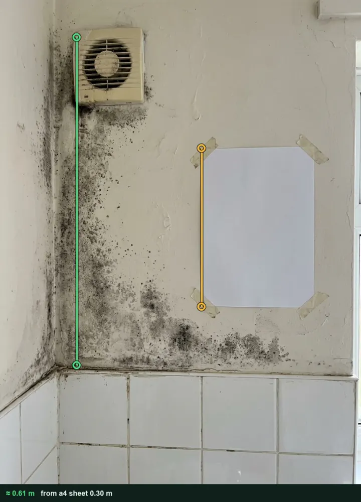 Mould on a bathroom wall below an extractor fan, measured from a photo at about 0.61 m high using an A4 sheet