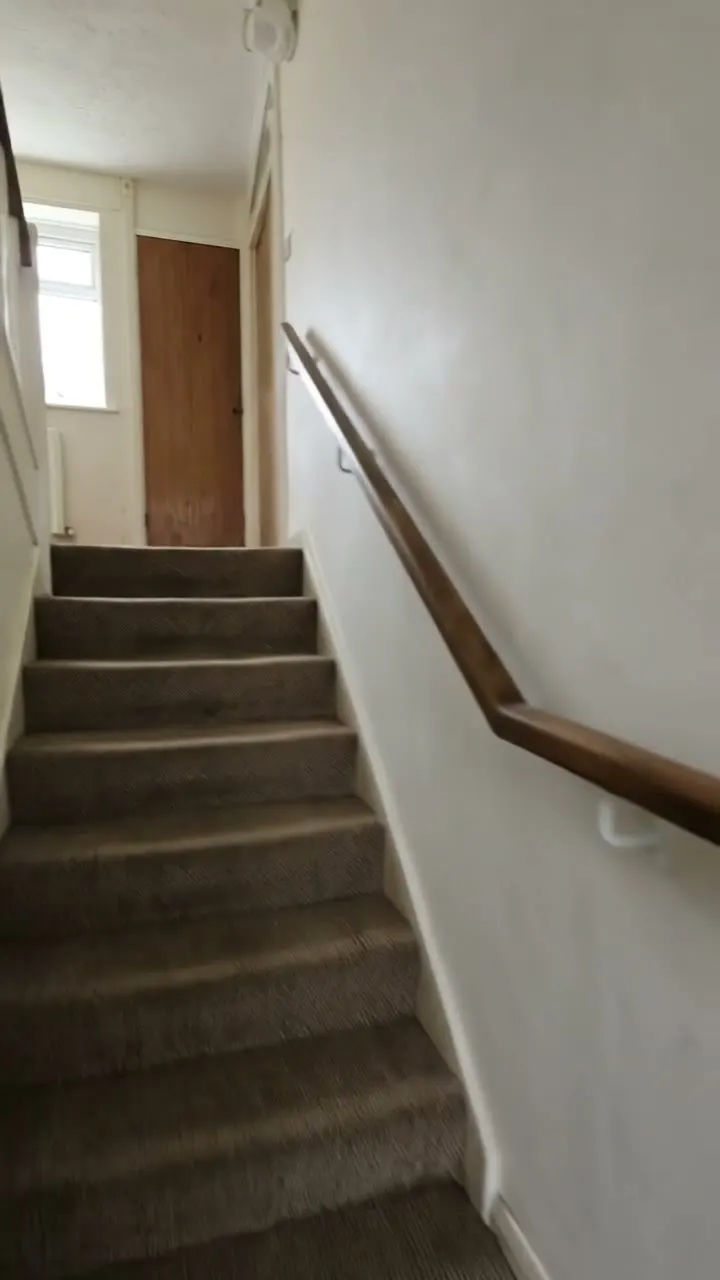 A staircase with a timber handrail on the wall