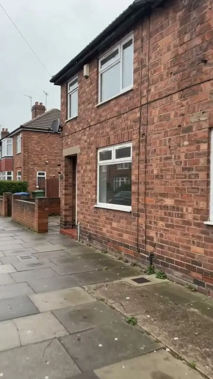 The front of an empty two-storey brick building with a dark front door