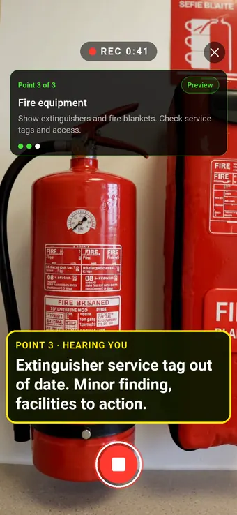 A fire extinguisher and fire blanket on an office kitchen wall, with the Walk Cam point card and live transcription