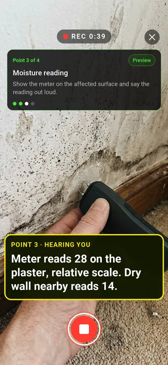 A moisture meter pressed against a mould-stained wall, with the Walk Cam point card and live transcription