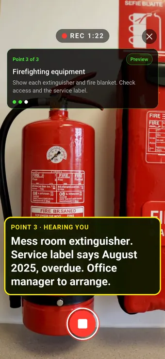 A wall-mounted extinguisher and fire blanket in a mess room kitchenette, with the Walk Cam point card and live transcription