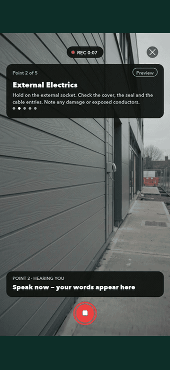 An electrical inspection point in SiteSurvey Walk Cam — filming an external socket while live voice-to-text writes the observation about a smashed cover and exposed conductors