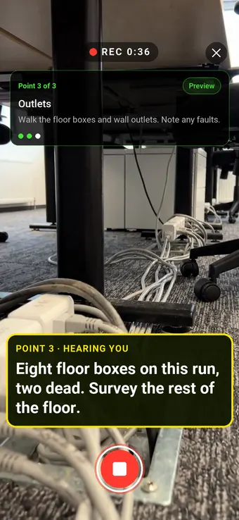 Floor boxes and outlets under a row of office desks, with the Walk Cam point card and live transcription