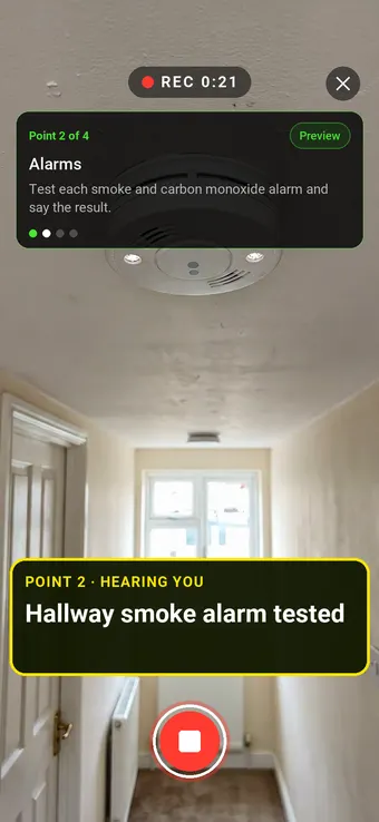 A finger pressing the test button on a hallway smoke alarm, with the Walk Cam point card and live transcription
