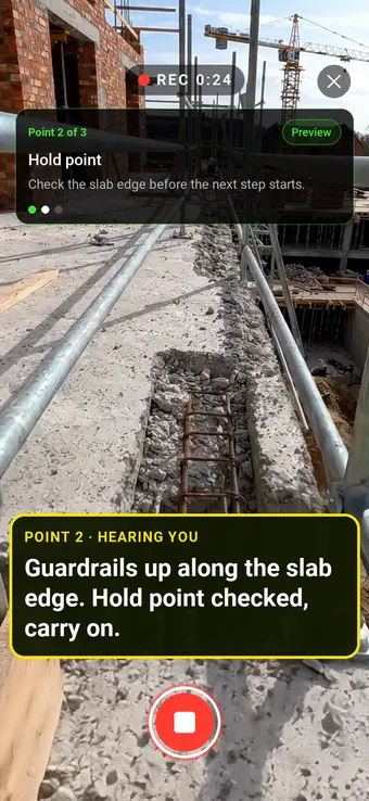 Guardrails along a first floor slab edge with rebar in the beam below, with the Walk Cam point card and live transcription
